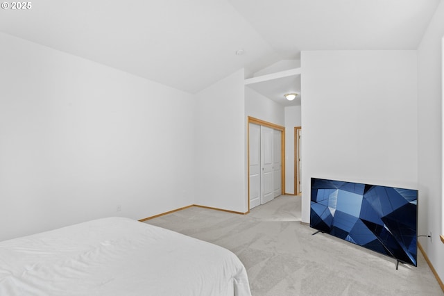 bedroom featuring carpet floors, baseboards, lofted ceiling, and a closet