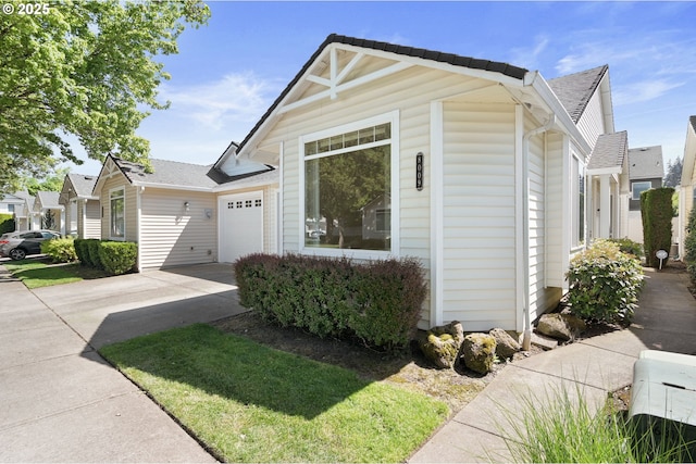 view of front facade featuring a garage, roof with shingles, and concrete driveway