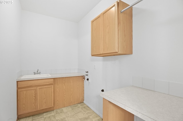 washroom with cabinet space, baseboards, and a sink