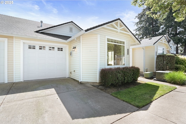 view of front of home with a garage, cooling unit, roof with shingles, and concrete driveway