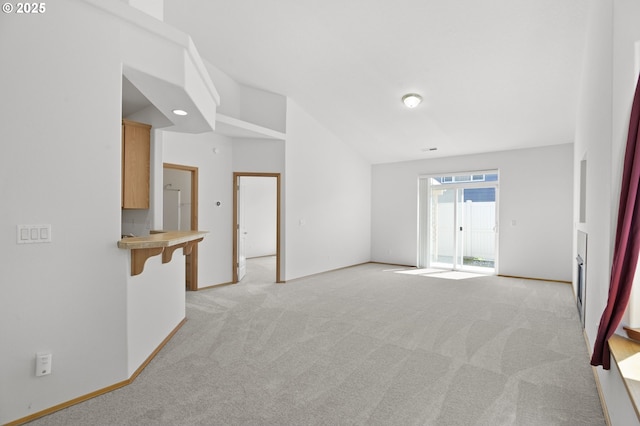 empty room featuring baseboards, lofted ceiling, and light carpet