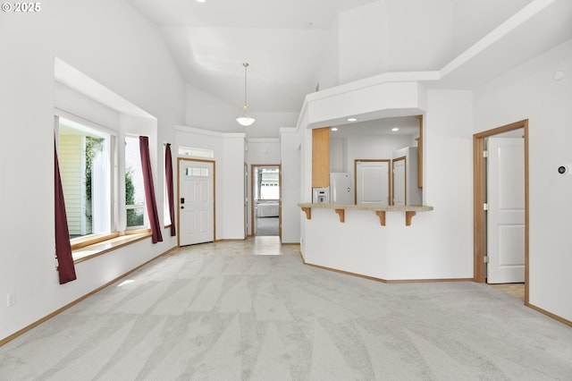 unfurnished living room featuring baseboards, light colored carpet, and vaulted ceiling