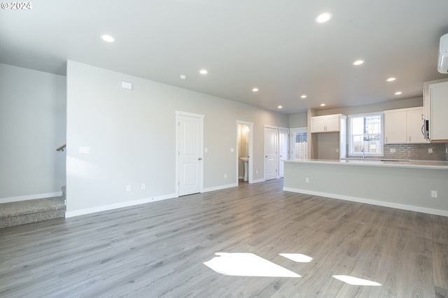 unfurnished living room featuring sink and light hardwood / wood-style flooring