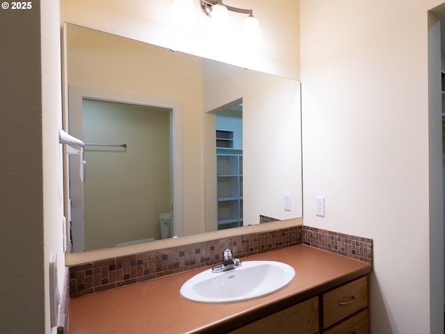 bathroom featuring vanity, toilet, and backsplash