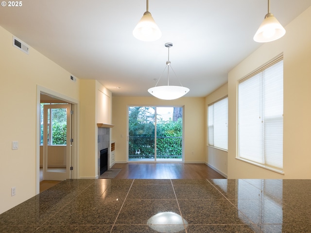 unfurnished living room featuring a tile fireplace and a healthy amount of sunlight