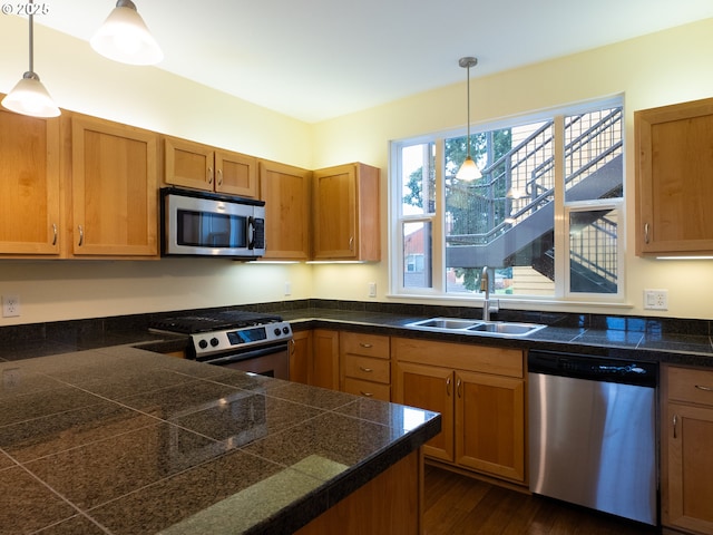 kitchen featuring dark hardwood / wood-style flooring, sink, decorative light fixtures, and appliances with stainless steel finishes