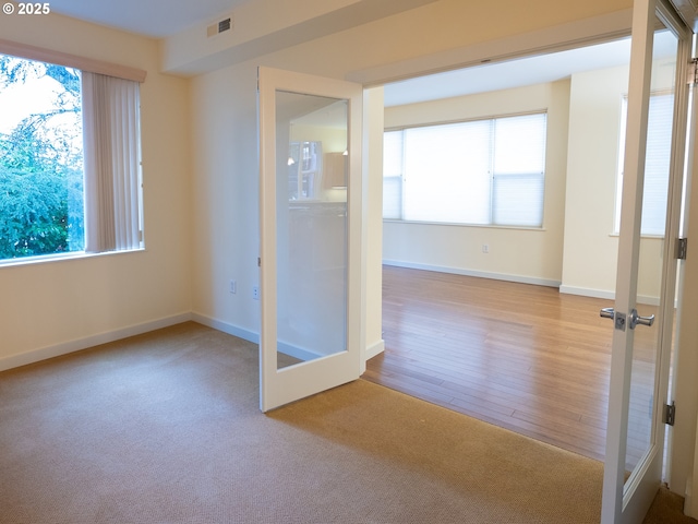 carpeted empty room featuring french doors and a wealth of natural light