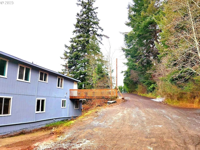 view of side of property with dirt driveway and a deck