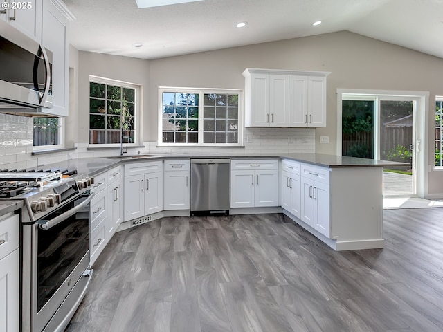 907 NW 90th St, Vancouver, WA 98665 - kitchen featuring appliances with stainless steel finishes, a peninsula, lofted ceiling, white cabinets, and backsplash