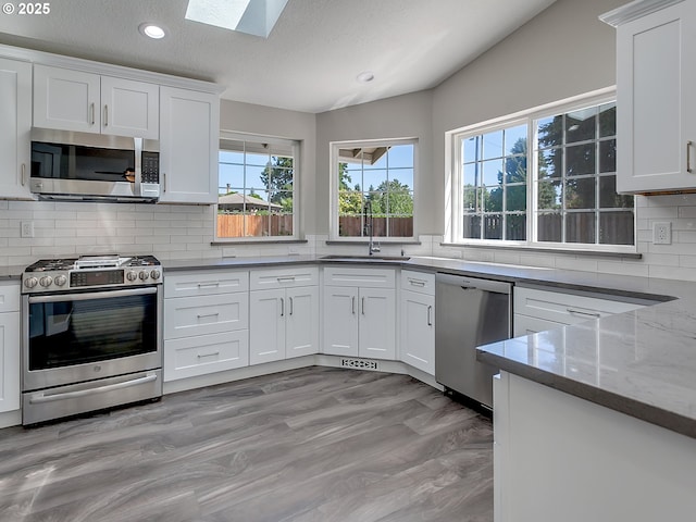 907 NW 90th St, Vancouver, WA 98665 - kitchen with stainless steel appliances, a skylight, recessed lighting, white cabinets, and backsplash