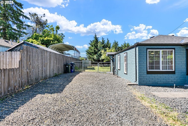 2745 C St, Springfield, OR 97477 - view of home's exterior featuring a detached carport, brick siding, a gate, and roof with shingles