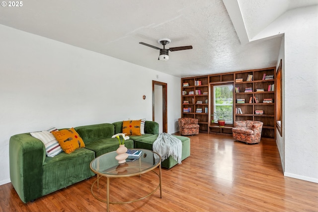 living room featuring built in features, baseboards, ceiling fan, and wood finished floors
