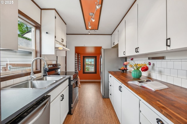 kitchen with white cabinets, appliances with stainless steel finishes, a sink, under cabinet range hood, and butcher block counters