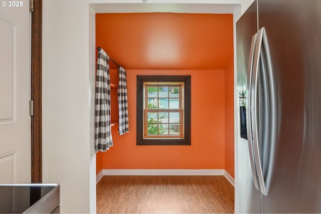 interior space featuring stainless steel fridge and baseboards
