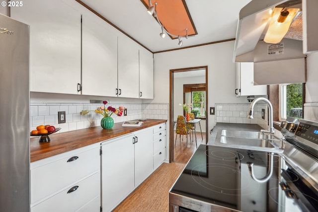 kitchen featuring a sink, white cabinets, backsplash, and butcher block counters