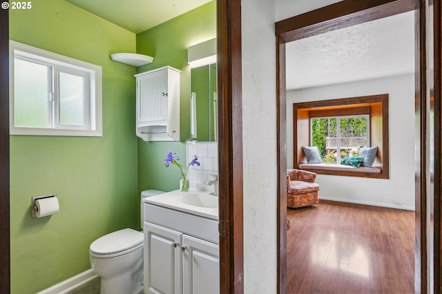 bathroom featuring baseboards, vanity, toilet, and wood finished floors
