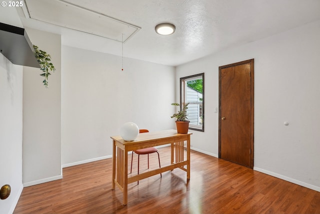 office with baseboards, attic access, and wood finished floors