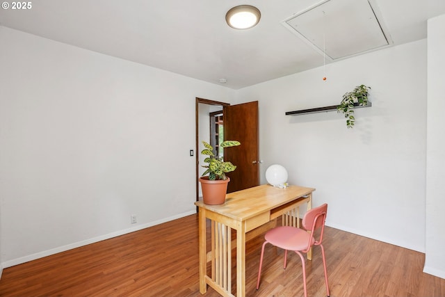 home office featuring light wood-type flooring, attic access, and baseboards