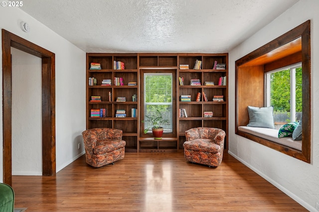 living area featuring baseboards, a textured ceiling, and wood finished floors