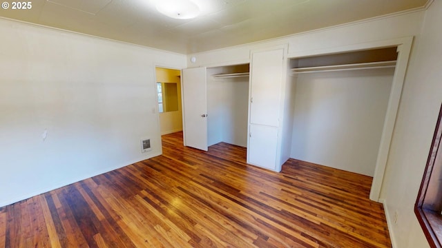 unfurnished bedroom with ornamental molding and dark wood-type flooring