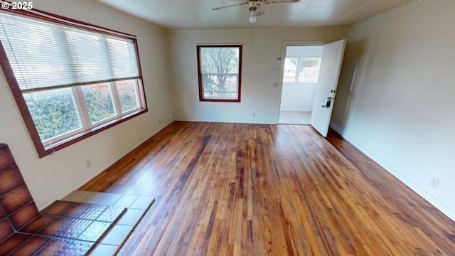 spare room with crown molding, a healthy amount of sunlight, ceiling fan, and dark hardwood / wood-style flooring