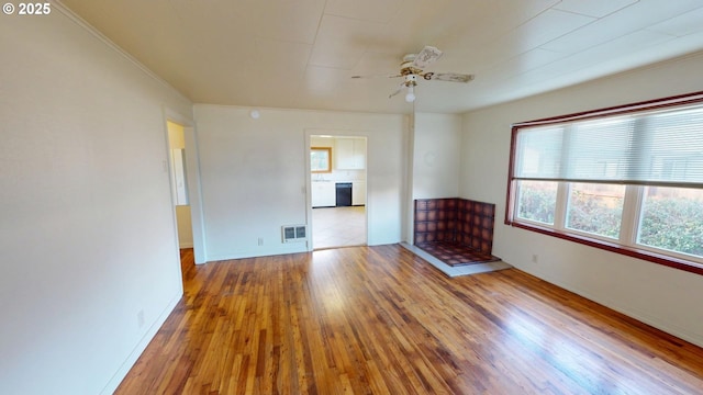 unfurnished living room featuring hardwood / wood-style flooring, ceiling fan, crown molding, and a fireplace