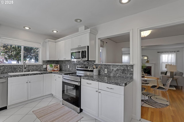 4580 NE 35th Pl, Portland, OR 97211 - kitchen with appliances with stainless steel finishes, a sink, white cabinets, decorative backsplash, and recessed lighting