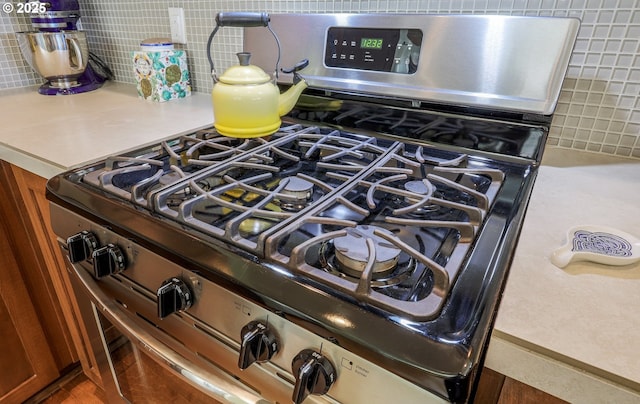 details with gas stove, light countertops, and backsplash