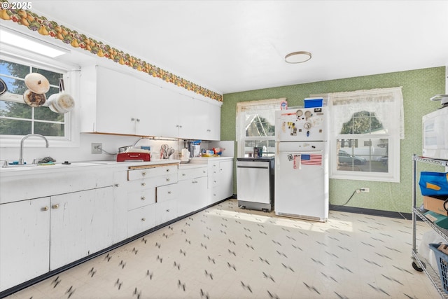 kitchen featuring stainless steel dishwasher, sink, white fridge, and white cabinets