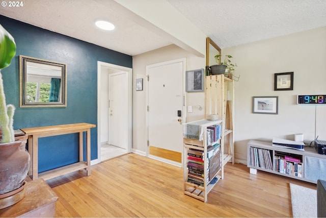interior space with a textured ceiling, wood finished floors, and baseboards
