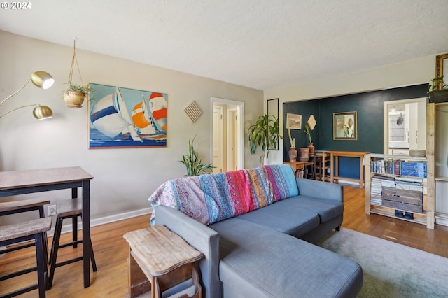 living area with baseboards, wood finished floors, and a textured ceiling