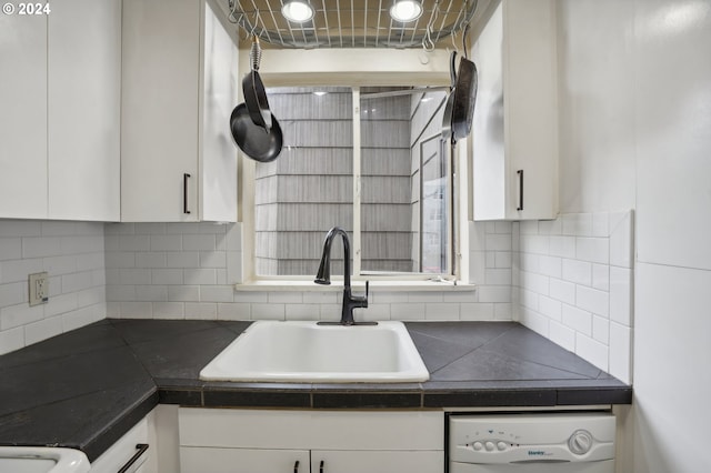 kitchen with white cabinets, dishwasher, a sink, and dark countertops
