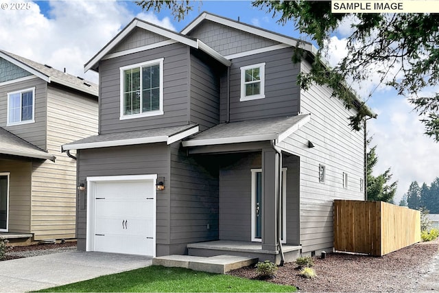 view of front of home with concrete driveway, fence, a garage, and a shingled roof