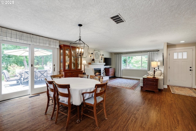 2648 SE Risley Ave, Milwaukie, OR 97267 - dining area with dark wood-type flooring, a textured ceiling, a glass covered fireplace, and a chandelier