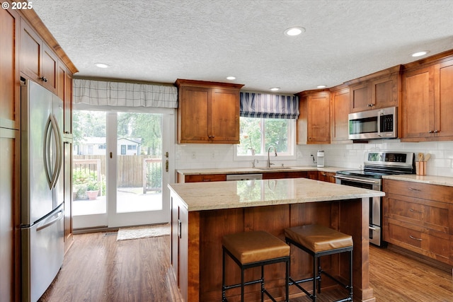 2648 SE Risley Ave, Milwaukie, OR 97267 - kitchen featuring appliances with stainless steel finishes, wood finished floors, a textured ceiling, brown cabinets, and tasteful backsplash