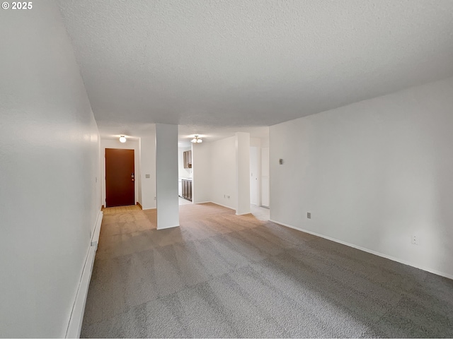 spare room featuring light carpet, baseboards, and a textured ceiling