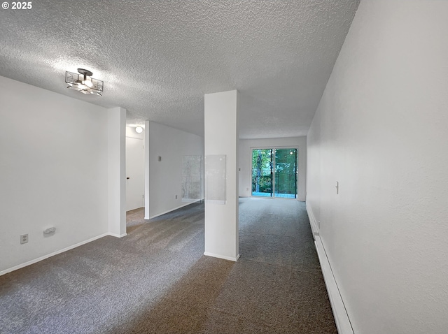 empty room with a textured ceiling, dark colored carpet, and baseboards