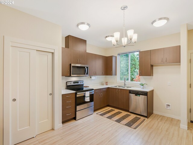 kitchen featuring appliances with stainless steel finishes, sink, a notable chandelier, and decorative light fixtures