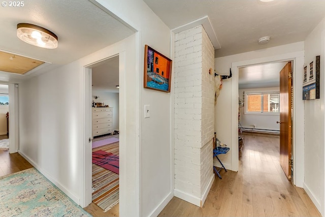 hallway with light wood-type flooring and baseboard heating