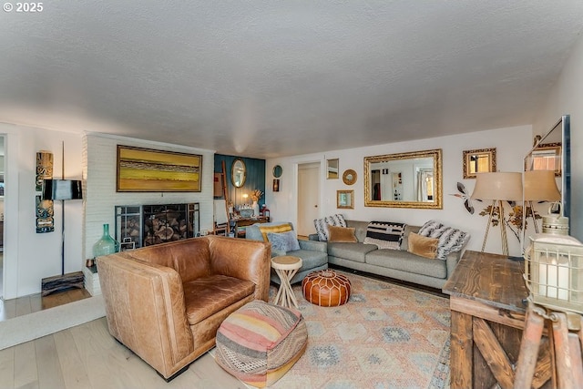 living room featuring a brick fireplace, light hardwood / wood-style flooring, and a textured ceiling