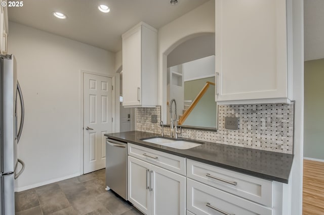 kitchen with dark countertops, backsplash, appliances with stainless steel finishes, and a sink