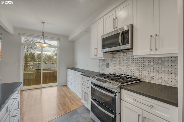 kitchen with dark countertops, backsplash, and appliances with stainless steel finishes