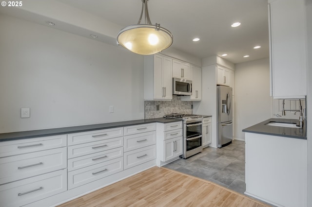 kitchen featuring dark countertops, backsplash, appliances with stainless steel finishes, and a sink