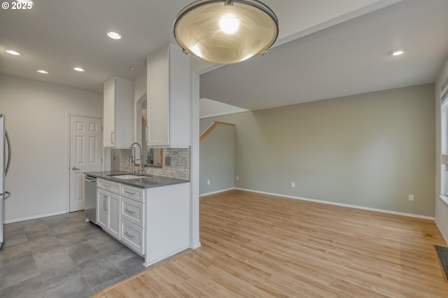 kitchen with dark countertops, decorative backsplash, appliances with stainless steel finishes, white cabinets, and a sink