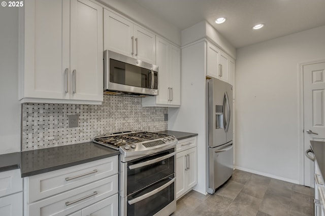 kitchen with decorative backsplash, dark countertops, appliances with stainless steel finishes, and white cabinetry