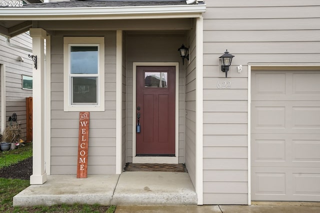 entrance to property featuring a garage and roof with shingles