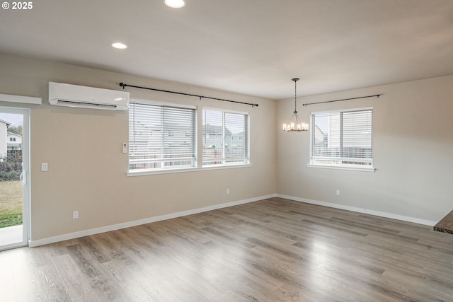 spare room featuring a wall unit AC, wood finished floors, and a wealth of natural light