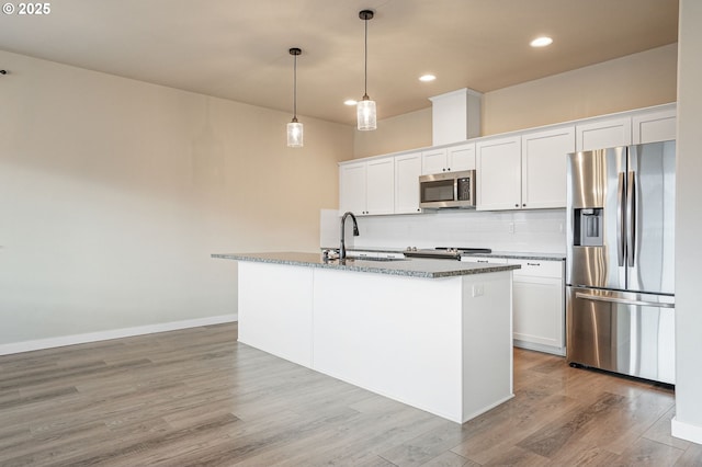 kitchen featuring appliances with stainless steel finishes, white cabinetry, a center island with sink, and a sink