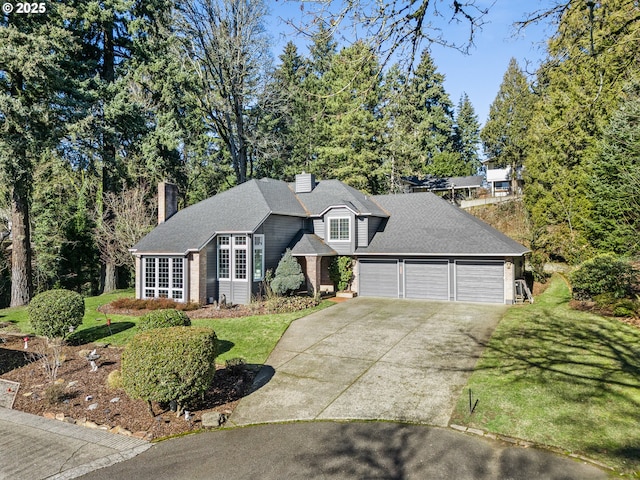 view of front facade featuring roof with shingles, a chimney, concrete driveway, an attached garage, and a front yard