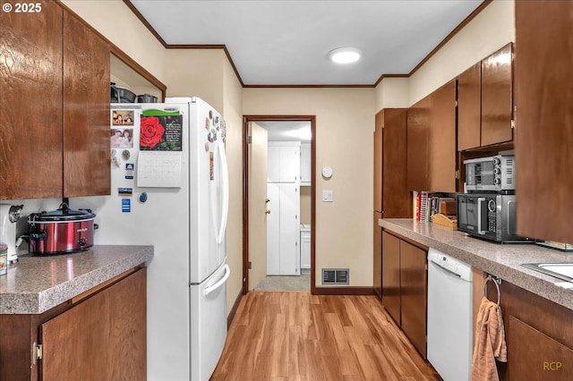 kitchen with light wood finished floors, visible vents, crown molding, tile countertops, and white appliances